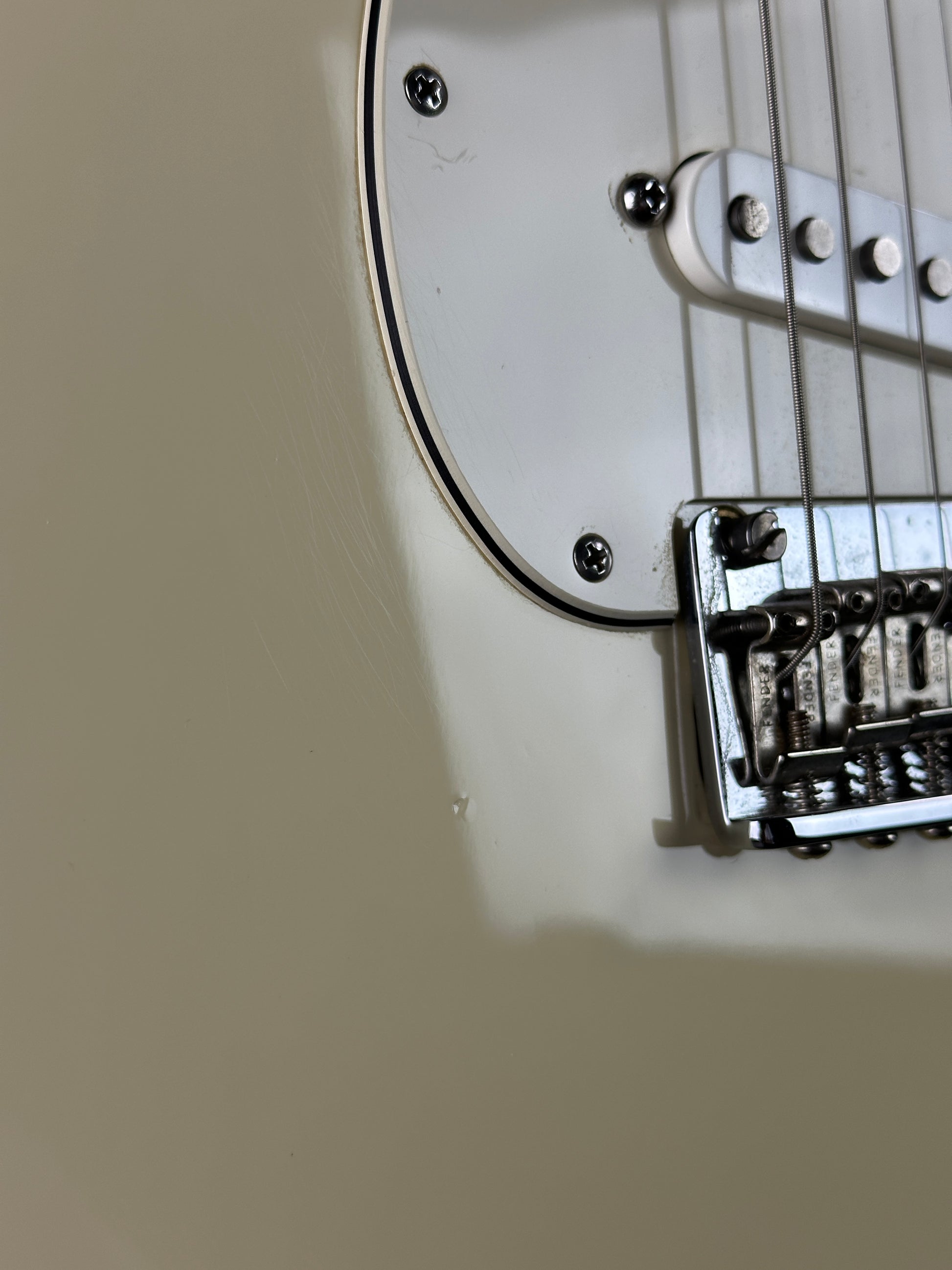 Close-up of a guitar's bridge and strings on a beige background