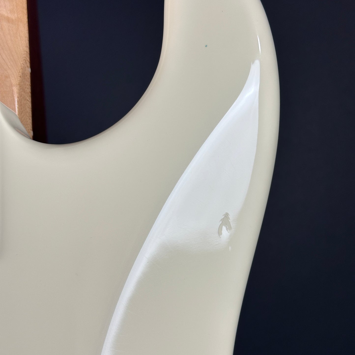 Close-up of a guitar neck with a white pickguard on a dark background