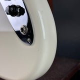 Close-up of a glossy off-white electric guitar body showing part of the chrome hardware and control knob against a dark background.