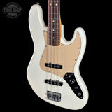 A white electric bass guitar with a beige pickguard, black hardware, and a dark wood fretboard, shown against a solid black background with a Tone Shop watermark in the top-left corner.