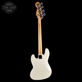 A single-cutaway electric bass guitar shown from the back, featuring an off-white body, a natural wood neck, and black tuning pegs, photographed against a solid black background.