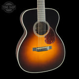 Acoustic guitar with a sunburst finish on a black background, featuring the Tone Shop logo.