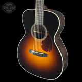 Acoustic guitar with a sunburst finish on a black background, featuring the Tone Shop logo.