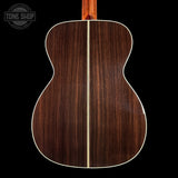 Back view of a wooden acoustic guitar with 'Tone Shop' logo in the corner.