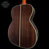 Back view of a wooden acoustic guitar with a visible brand logo in the corner.