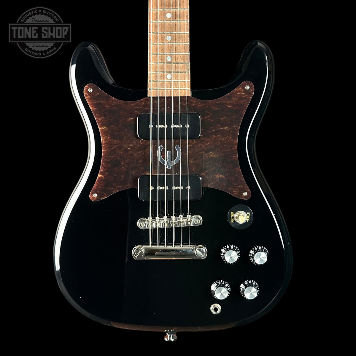 Black electric guitar with a wooden fretboard on a black background, featuring the Tone Shop logo.