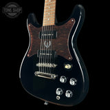 Black electric guitar with a visible brand logo on a black background