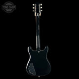 Black electric guitar on a black background with 'Tone Shop' logo.