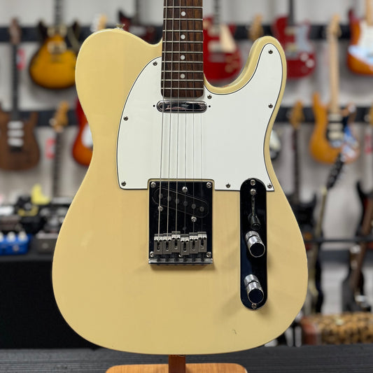 Beige electric guitar on a stand with a blurred background of other guitars