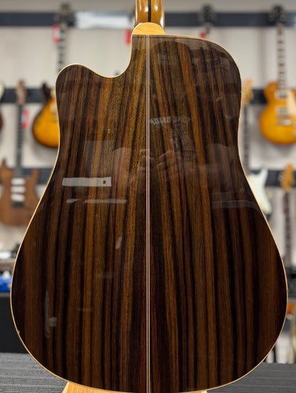 Close-up of a guitar's back with a wood grain pattern, blurred background of a music store.