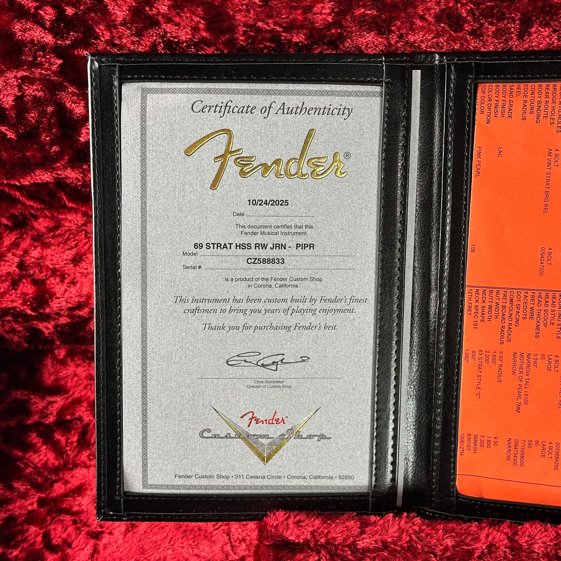 Fender certificate of authenticity and document on a red textured surface