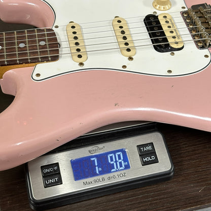 Pink electric guitar on a digital scale displaying weight.