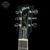 Close-up of a Gibson Les Paul Standard electric guitar headstock, showing the Gibson logo, Les Paul Model text, and six tuning pegs against a black background.