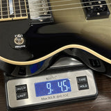 A close-up of a black electric guitar body resting on a digital scale displaying 9.45 lbs, with the scale showing brand logo 'Kershaw'.