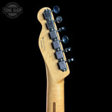 Close-up of the headstock of a Fender electric guitar, showing the maple wood neck and six black tuning pegs against a solid black background.