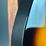 Close-up of a glossy black curved trim piece with a warm brown wood-grain surface visible in the background.