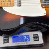 A close-up of a guitar body resting on a digital scale, showing the scale reading 7.123 oz.