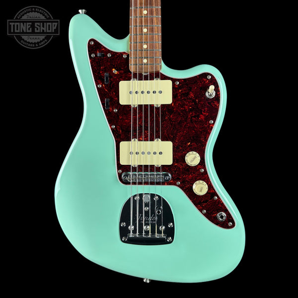 Electric guitar with a turquoise body and brown pickguard on a black background, featuring the Tone Shop logo.