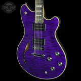 A purple electric guitar with a glossy, marbled quilted maple top, shown against a solid black background. The brand logo 'TONE SHOP' is visible in the top-left corner.