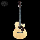 A natural wood acoustic-electric guitar with a cutaway body, dark fretboard, and black pickguard, shown against a solid black background with a Tone Shop watermark in the top-left corner.