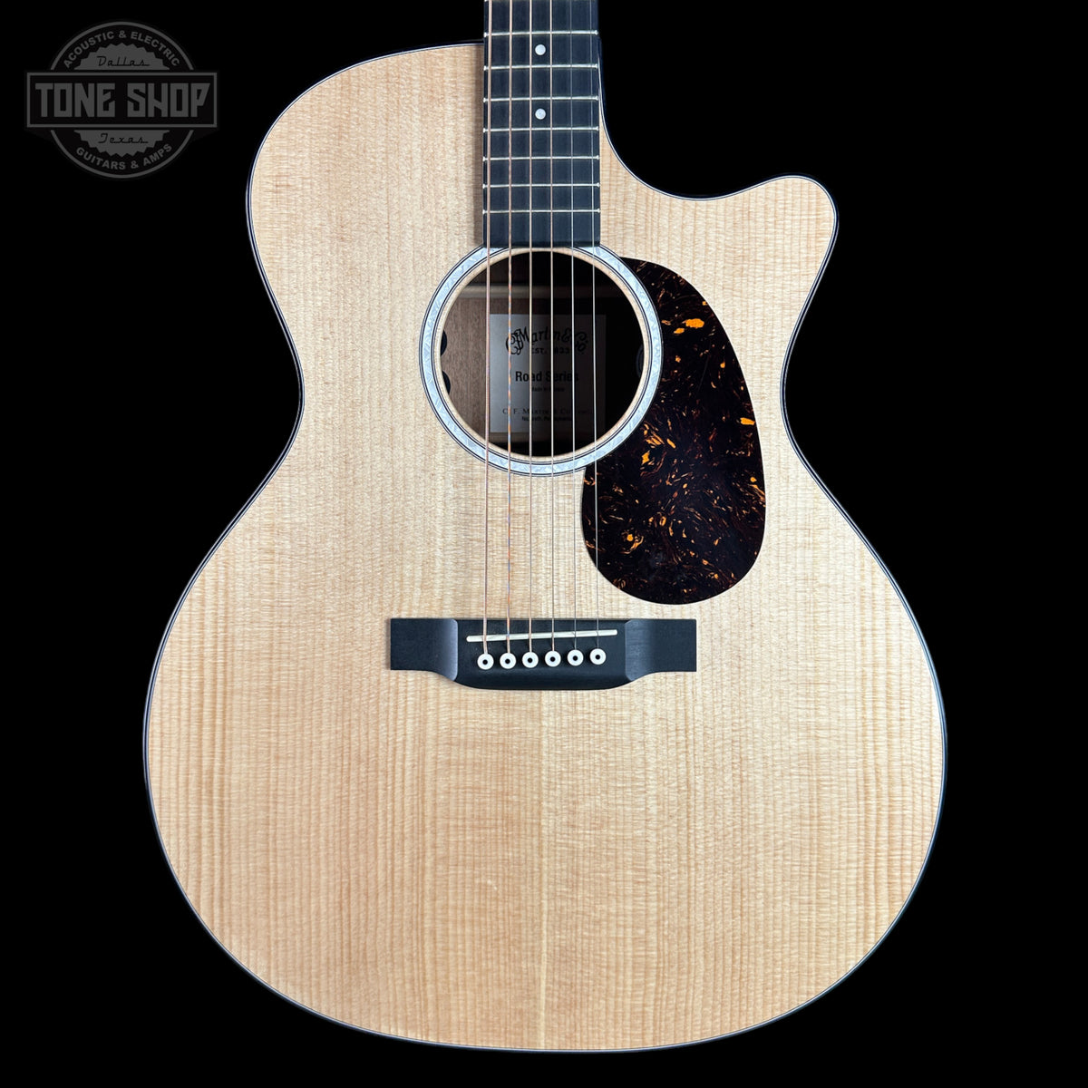 A Taylor acoustic guitar with a natural flamed maple top, black pickguard, and dark fretboard, shown against a solid black background. A 'TONE SHOP' watermark is visible in the top-left corner.