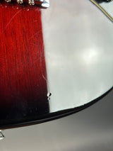Close-up of a guitar's soundhole with a red pickguard.