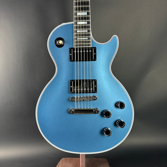 Blue electric guitar on a stand against a gray background