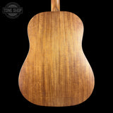 Back view of a wooden acoustic guitar with 'Tone Shop' logo in the corner.