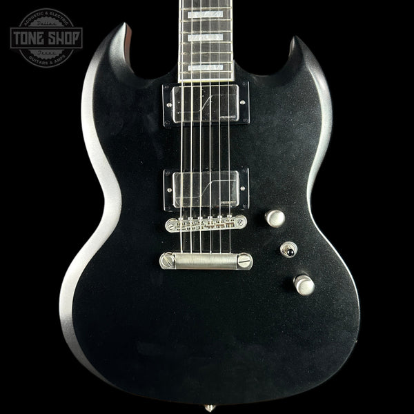 Black electric guitar with silver hardware on a black background, featuring 'Tone Shop' logo.