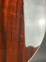 Close-up of a glossy reddish-brown wooden surface with a white reflective area near the top edge.