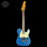 Blue electric guitar with a white pickguard on a black background, featuring the Tone Shop logo.