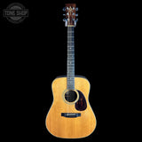 A vintage-style acoustic guitar with a natural wood finish, shown vertically against a solid black background. A circular 'TONE SHOP' watermark is visible in the top-left corner.