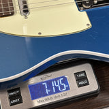 Blue electric guitar on a digital scale displaying weight