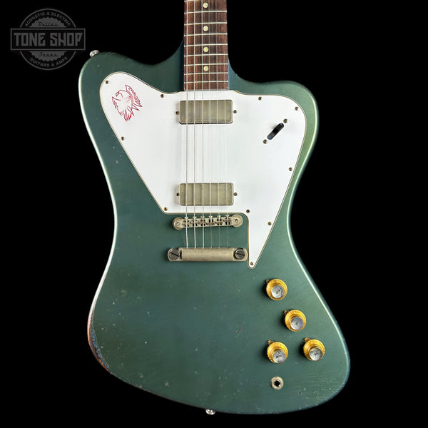 A green electric guitar with a white pickguard, chrome hardware, and gold control knobs, shown against a black background with a Tone Shop watermark.