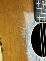 Close-up of an acoustic guitar body showing the natural wood grain, sound hole, neck joint, and part of the fretboard.