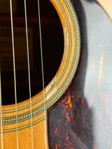 Close-up detail of an acoustic guitar showing the sound hole, decorative rosette inlay, strings, and part of the glossy dark brown tortoiseshell body.