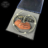 Guitar pickup with leather tag on a gray surface, branded 'Tone Shop'.