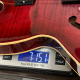 Guitar being weighed on a digital scale with a red finish