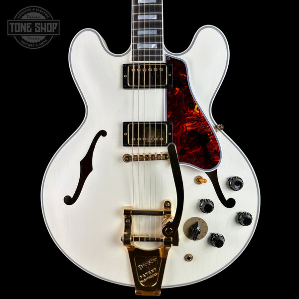 A white electric guitar with a red tortoiseshell pickguard and gold hardware, photographed against a solid black background. A Tone Shop watermark is visible in the top-left corner.
