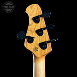 Close-up of a bass guitar headstock with a natural wood finish and black tuning pegs, shown against a solid black background with a Tone Shop watermark in the top left.