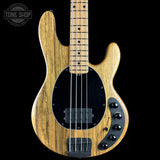 A natural wood four-string bass guitar with a black pickguard and control knobs, shown against a solid black background with a Tone Shop watermark in the top left corner.