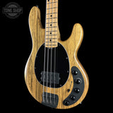 A natural wood bass guitar with black hardware and pickguard, shown against a solid black background with a Tone Shop watermark in the top left corner.