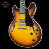 A vintage-style double-cutaway electric guitar with a sunburst finish, featuring a yellow-orange center fading to dark brown and black edges, set against a solid black background.