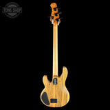 The back view of a natural wood electric bass guitar with a black pickguard and four tuning pegs, shown against a solid black background with a Tone Shop watermark in the top left corner.