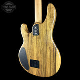 The back of a natural wood electric guitar, showing the glossy grain of the body and neck against a solid black background.