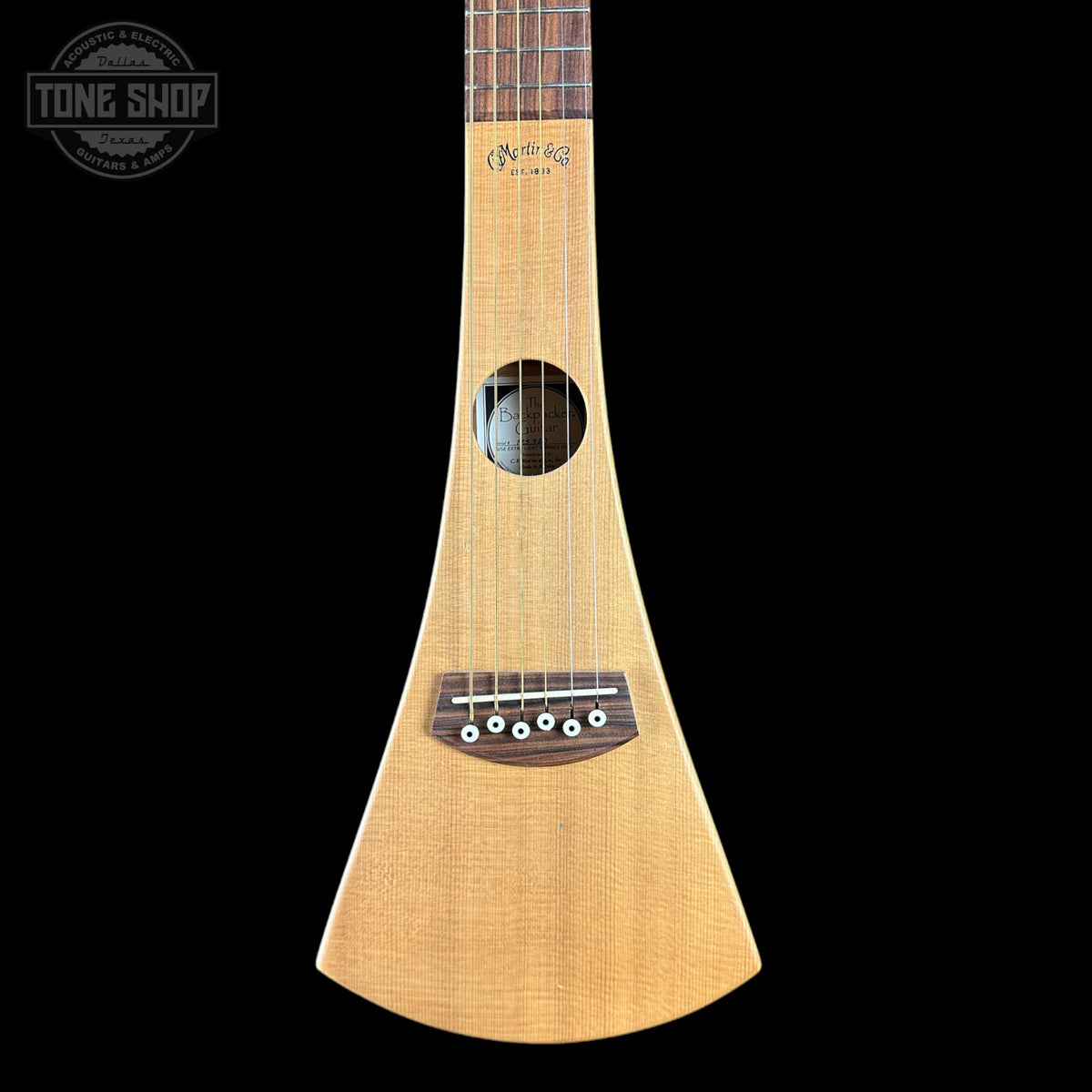 A natural wood soprano ukulele shown vertically against a solid black background, with a Tone Shop watermark in the upper left corner.