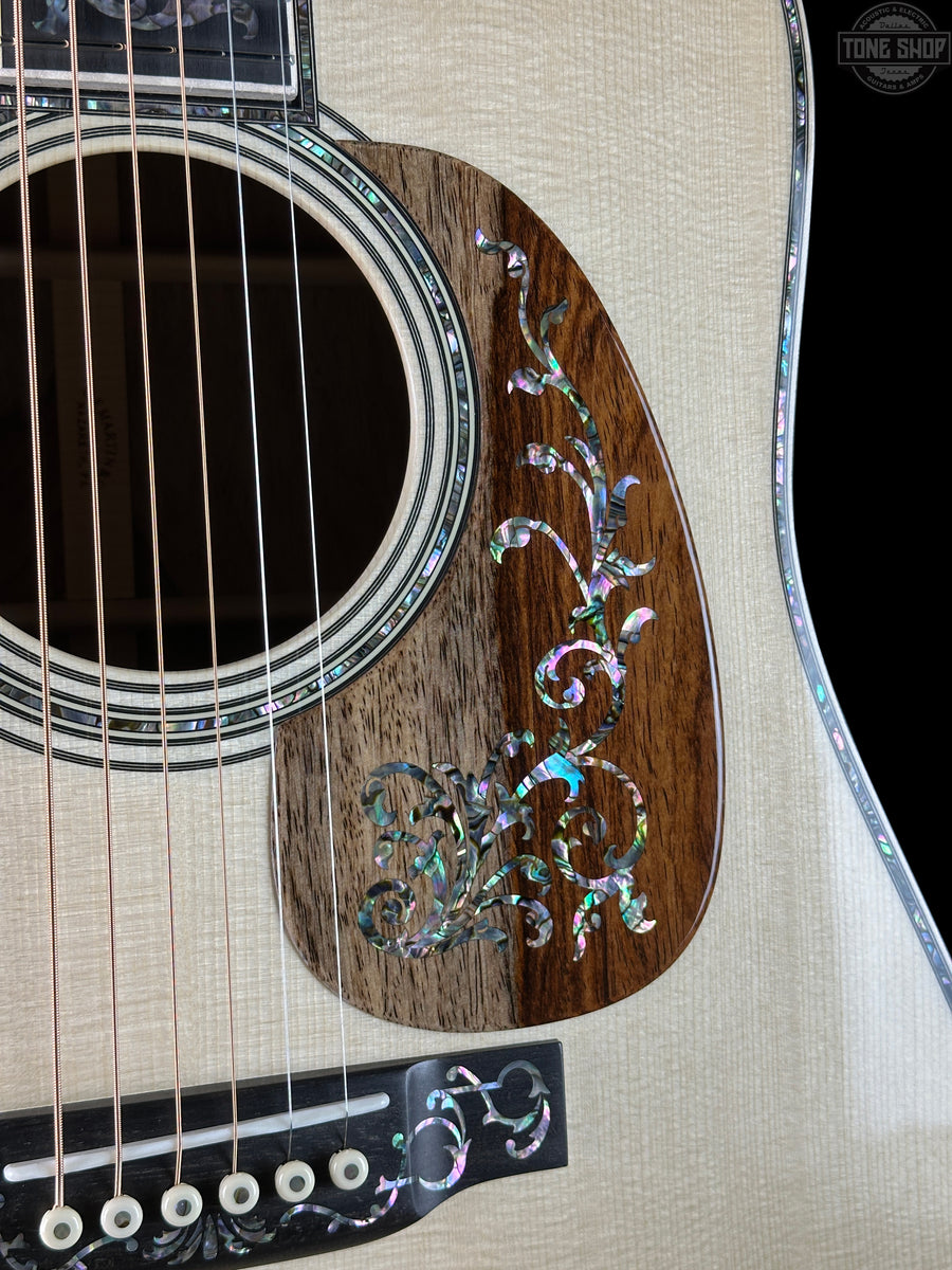 Inlaid rosewood pickguard on a martin guitar against a black background