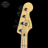 Close-up of a Fender Jazz Bass headstock made of natural maple wood, featuring four tuning pegs and chrome tuning keys, set against a solid black background.