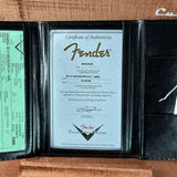 Fender certificate of authenticity in a black leather case on a wooden surface
