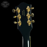 Close-up of a guitar headstock with gold tuning pegs on a black background, featuring 'Tone Shop' branding.